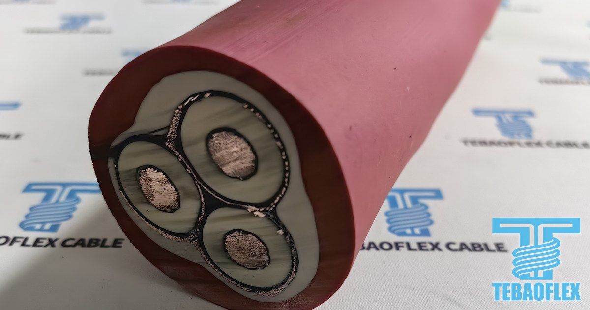 Cut end of a red (N)TSCGECEWÖU 12/20 kV cable showing three white-insulated cores, each wrapped in its own copper braid