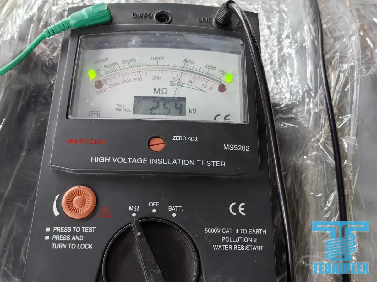 A MASTECH MS5202 high-voltage insulation tester resting on a plastic-wrapped cable drum, with its display showing 2.54 kV and its needle near the 5000 megohm mark