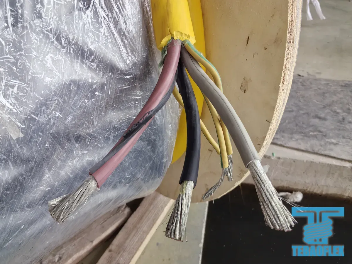 Stripped brown, black, grey and green-yellow cores at the end of a cable on its drum, with silver-coloured tinned strands